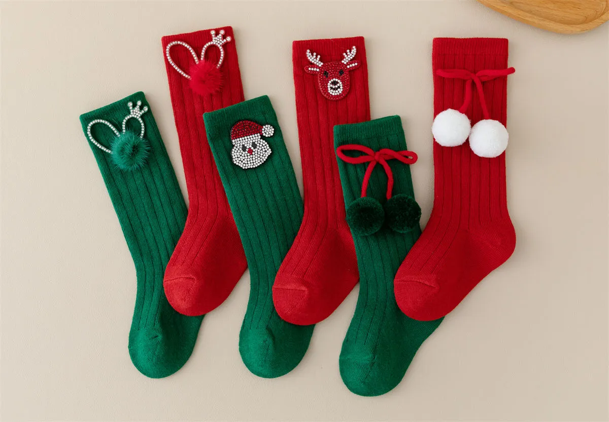 Close-up of red baby socks featuring a rhinestone crown and fluffy pom pom detail.
